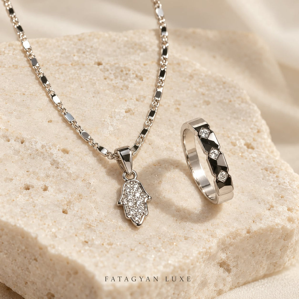 Noura Hamsa silver-tone crystal necklace and ring jewellery set on stone