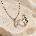 Noura Hamsa silver-tone crystal necklace and ring jewellery set on stone